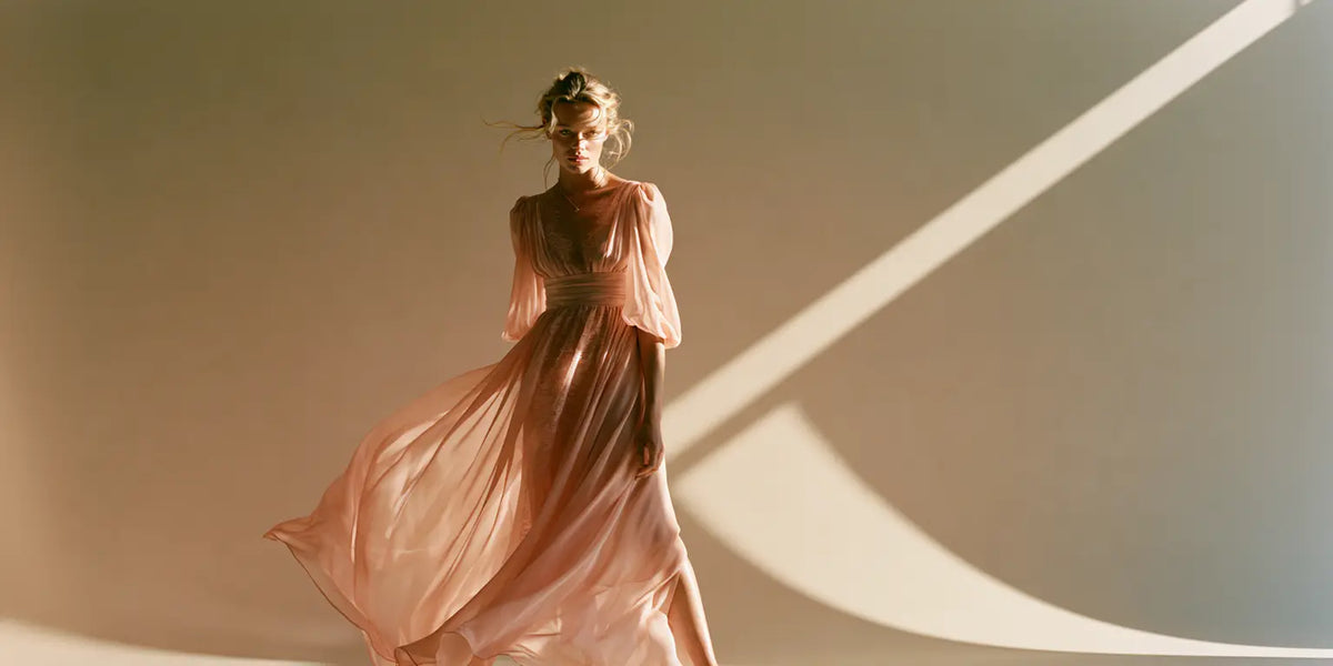Frau in fließendem Maxikleid aus blush-farbenem Chiffon mit Puffärmeln, in Bewegung vor warmem Hintergrund mit Schattenspiel – KI-Illustration