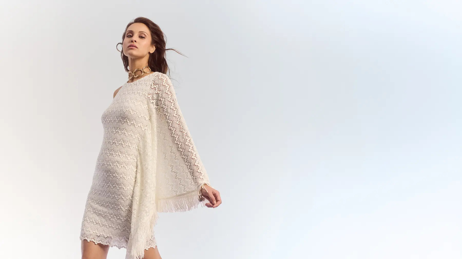 Model draagt een witte ajour-gebreide jurk met franjes van Ana Alcazar